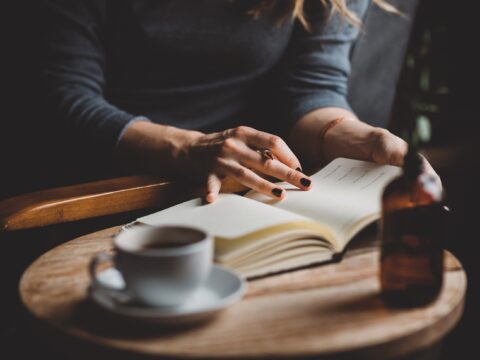 woman sits at table, looks at notepad