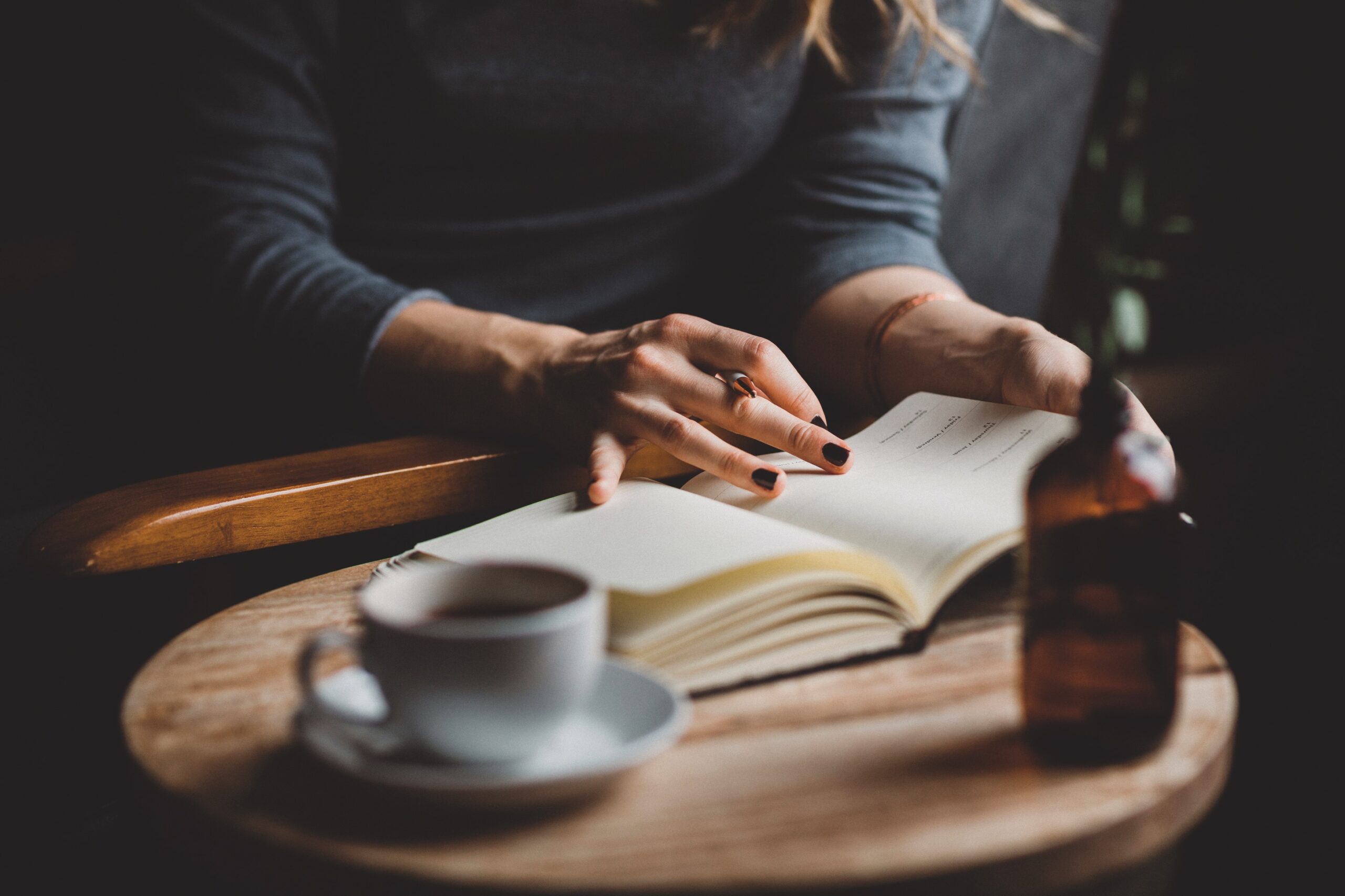 woman sits at table, looks at notepad