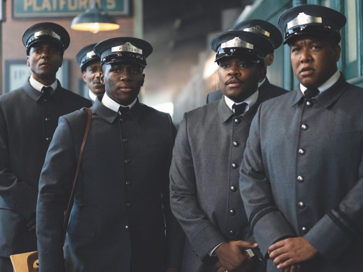 Four actors dressed up as railway porters are seen in a still from "The Porter."