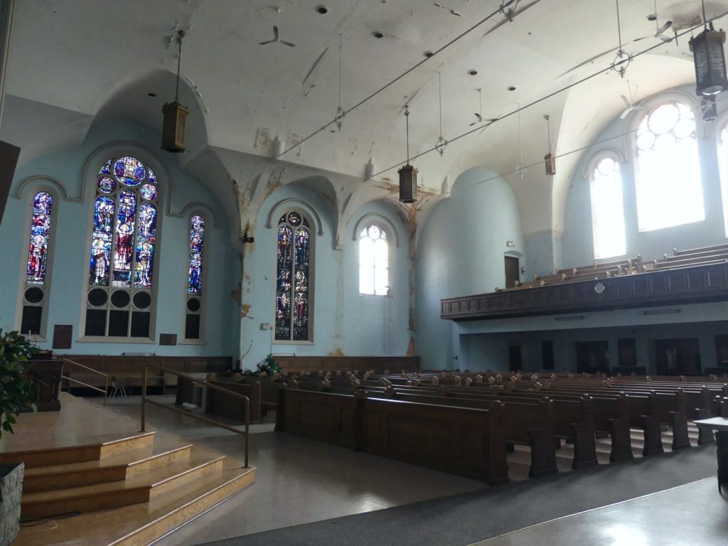Rows of pews and stained glass windows in the sanctuary of Saint Luke's 