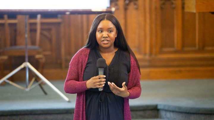 Jordana Wright speaks into a microphone inside the main congregating room of East End United Church