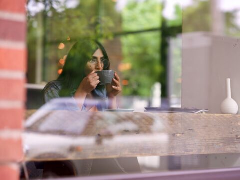 Woman in blue long-sleeved shirt drinking from mug