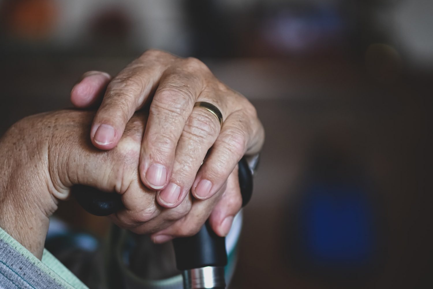 older person clasps hands on top of cane