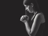 Woman praying with clasped hands