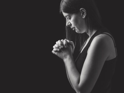 Woman praying with clasped hands