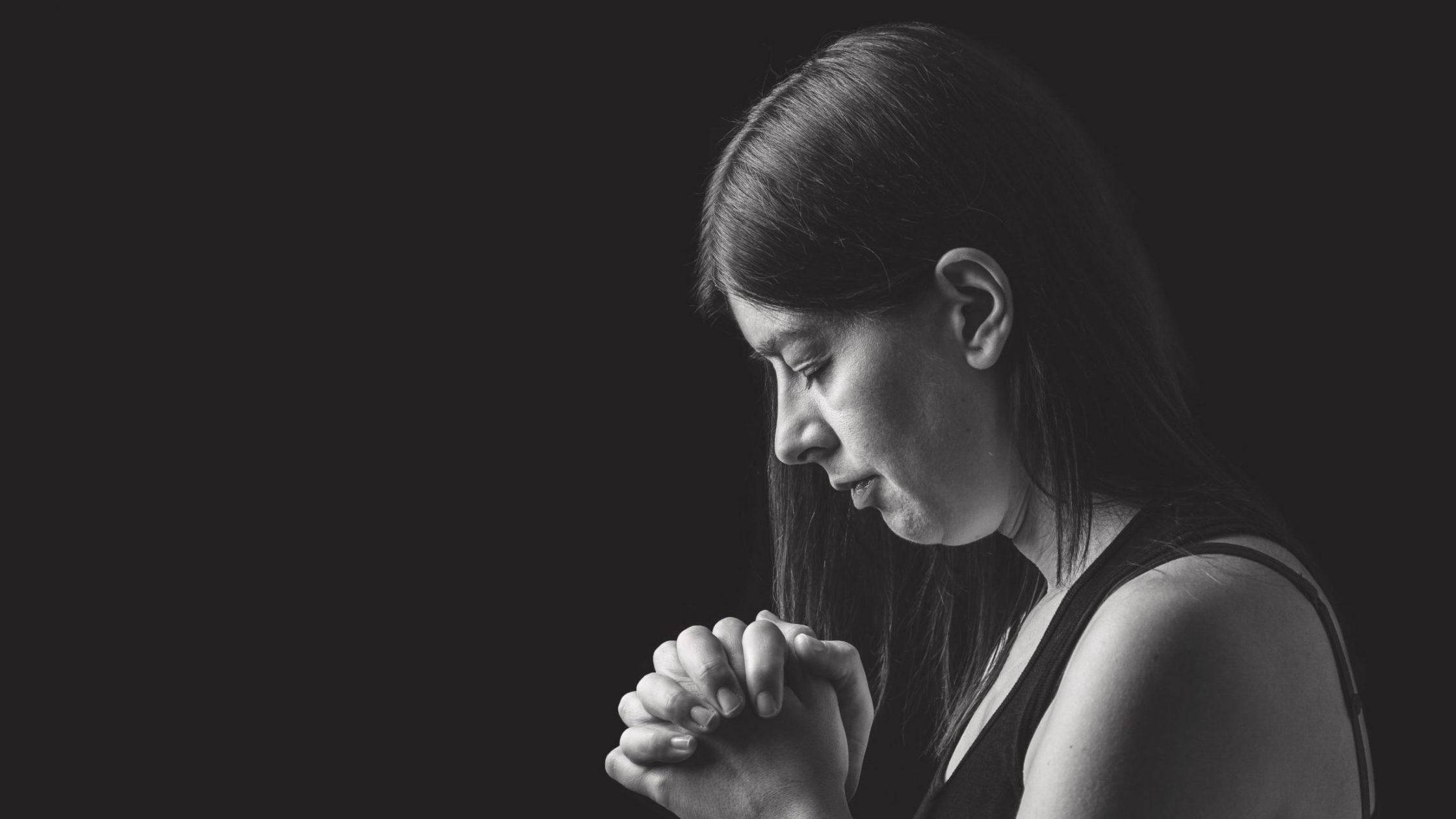 Woman praying with clasped hands