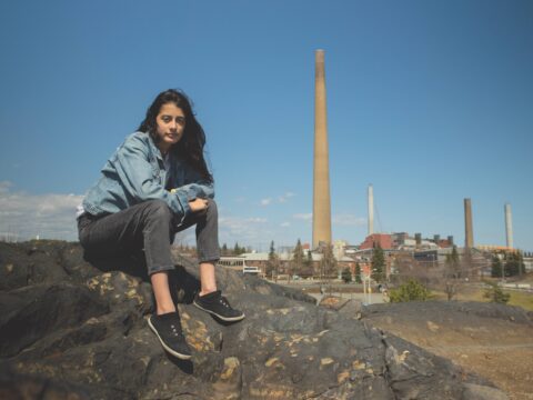 Youth Sophia Mather sits on a rock in Sudbury, Ontario.