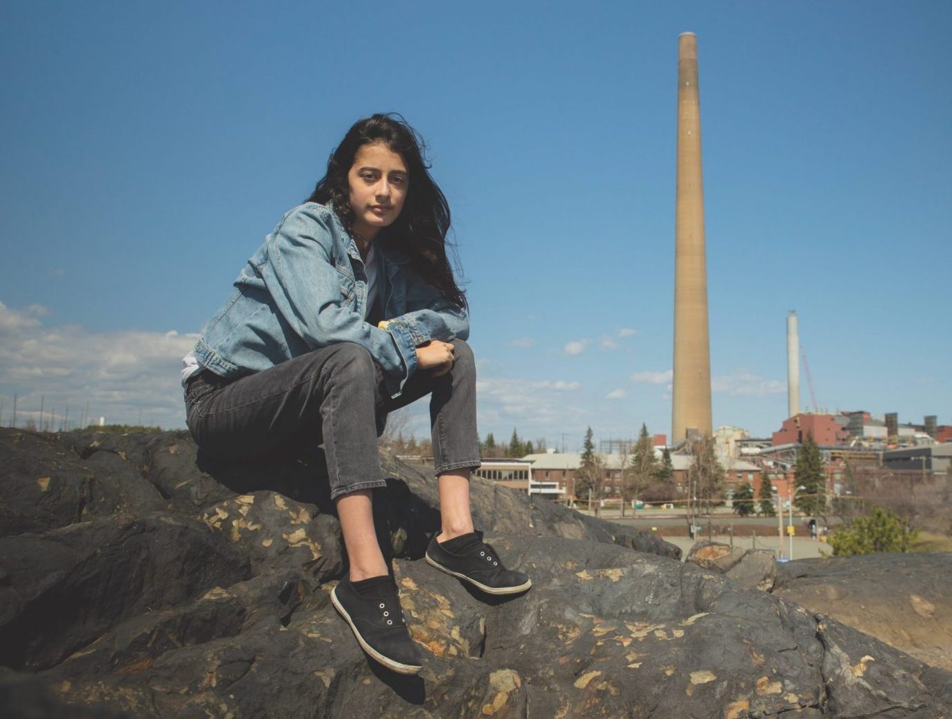Youth Sophia Mather sits on a rock in Sudbury, Ontario.