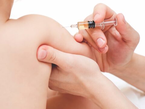 white baby getting injection in arm