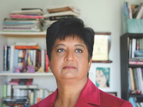 Asian woman in red shirt in front of bookcases