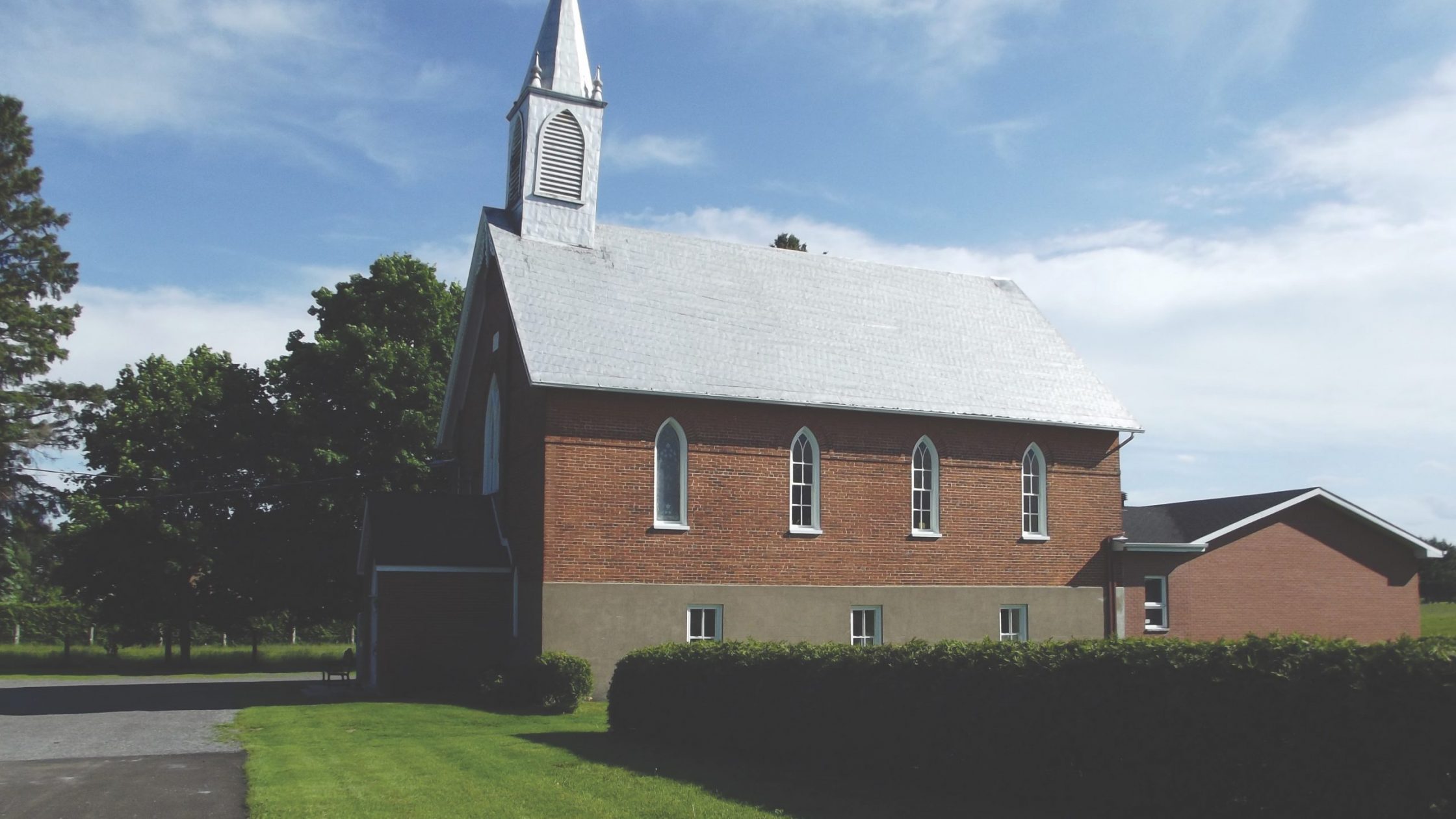 Brick church with green lawn and hedge