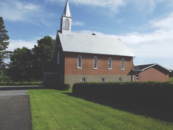 Brick church with green lawn and hedge