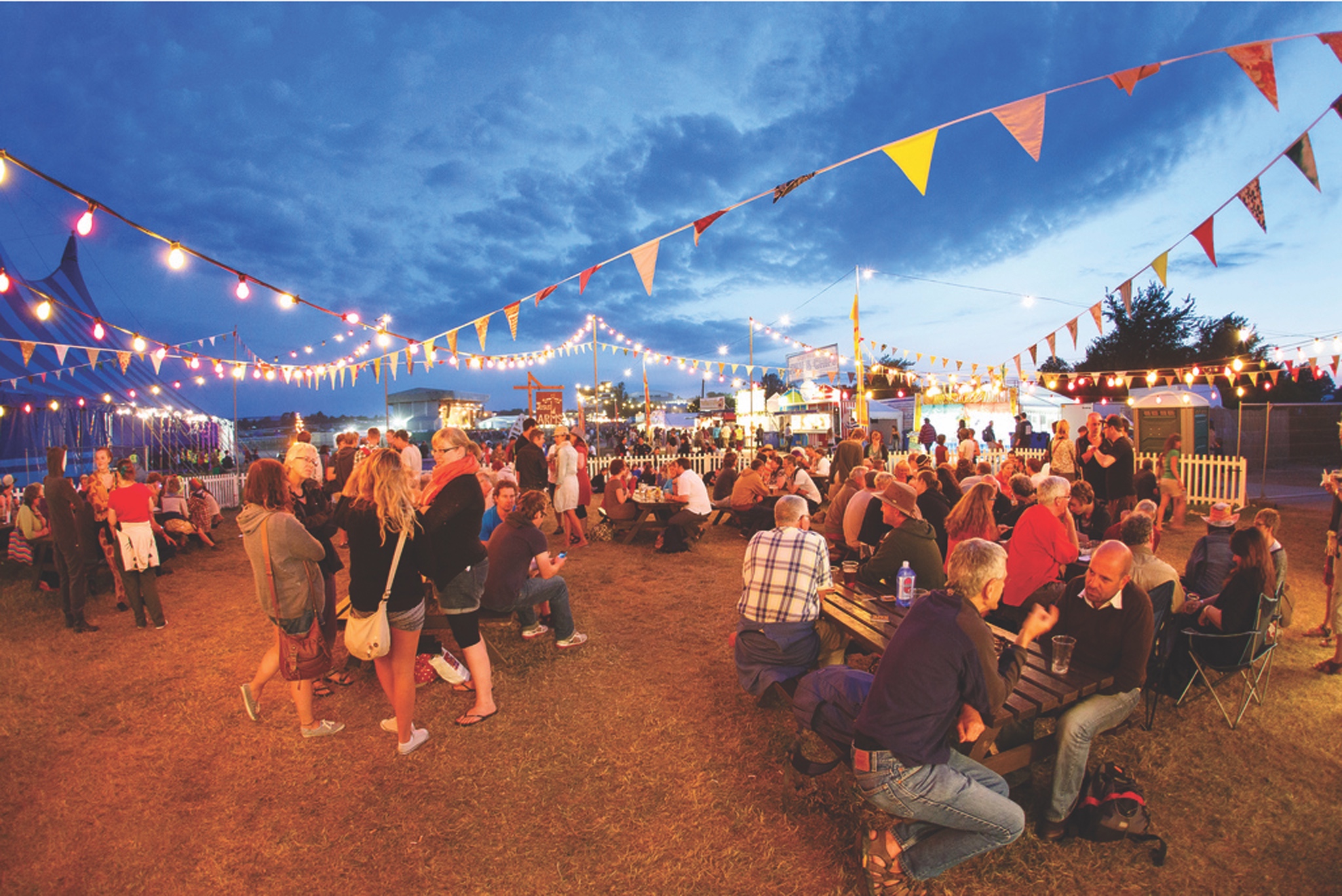 Many people sitting and standing at fairgrounds
