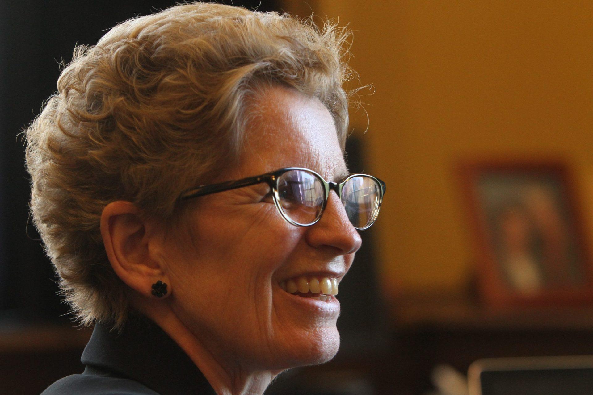 White woman with glasses in profile, smiling
