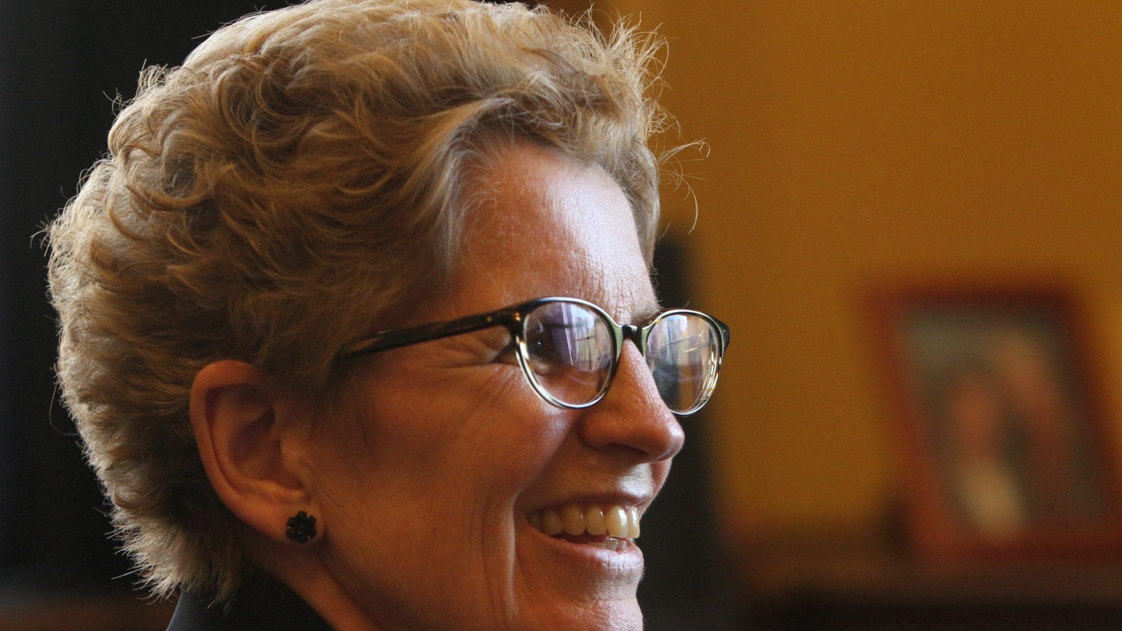 White woman with glasses in profile, smiling