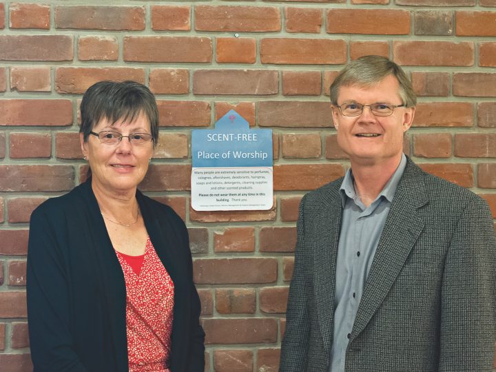 White man and woman in front of church wall