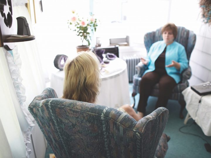 Blonde woman in chair facing dark-haired women