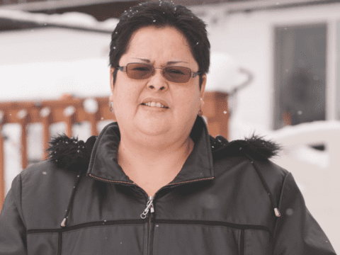 Indigenous woman in sunglasses and parka looking into camera