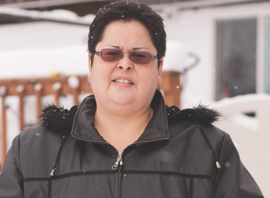 Indigenous woman in sunglasses and parka looking into camera