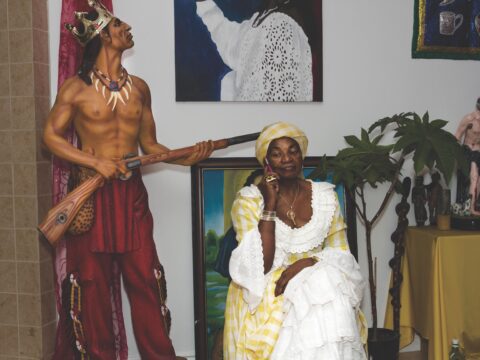 Vodou priestess in white and yellow dress and headdress on cell phone