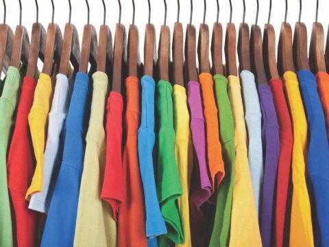 row of colourful T-shirts hanging on a rack