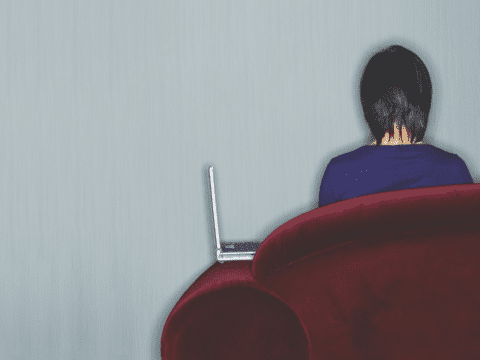 Woman with laptop on couch facing away