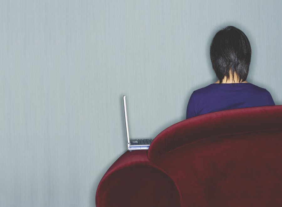 Woman with laptop on couch facing away