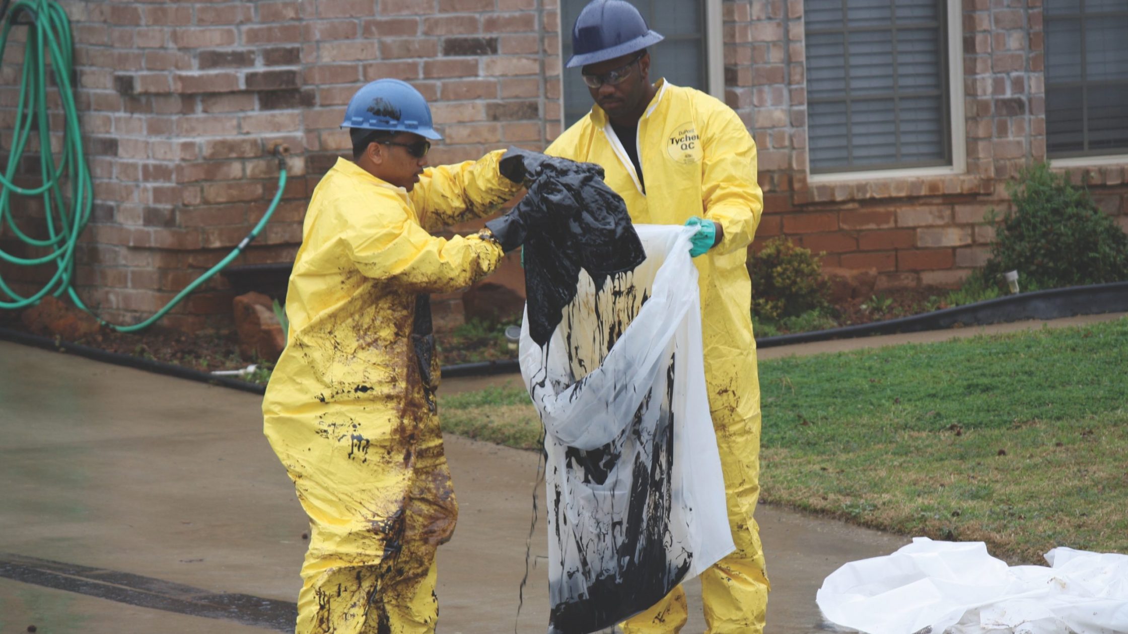 Men in hazmat suits put oil-soaked material in bags