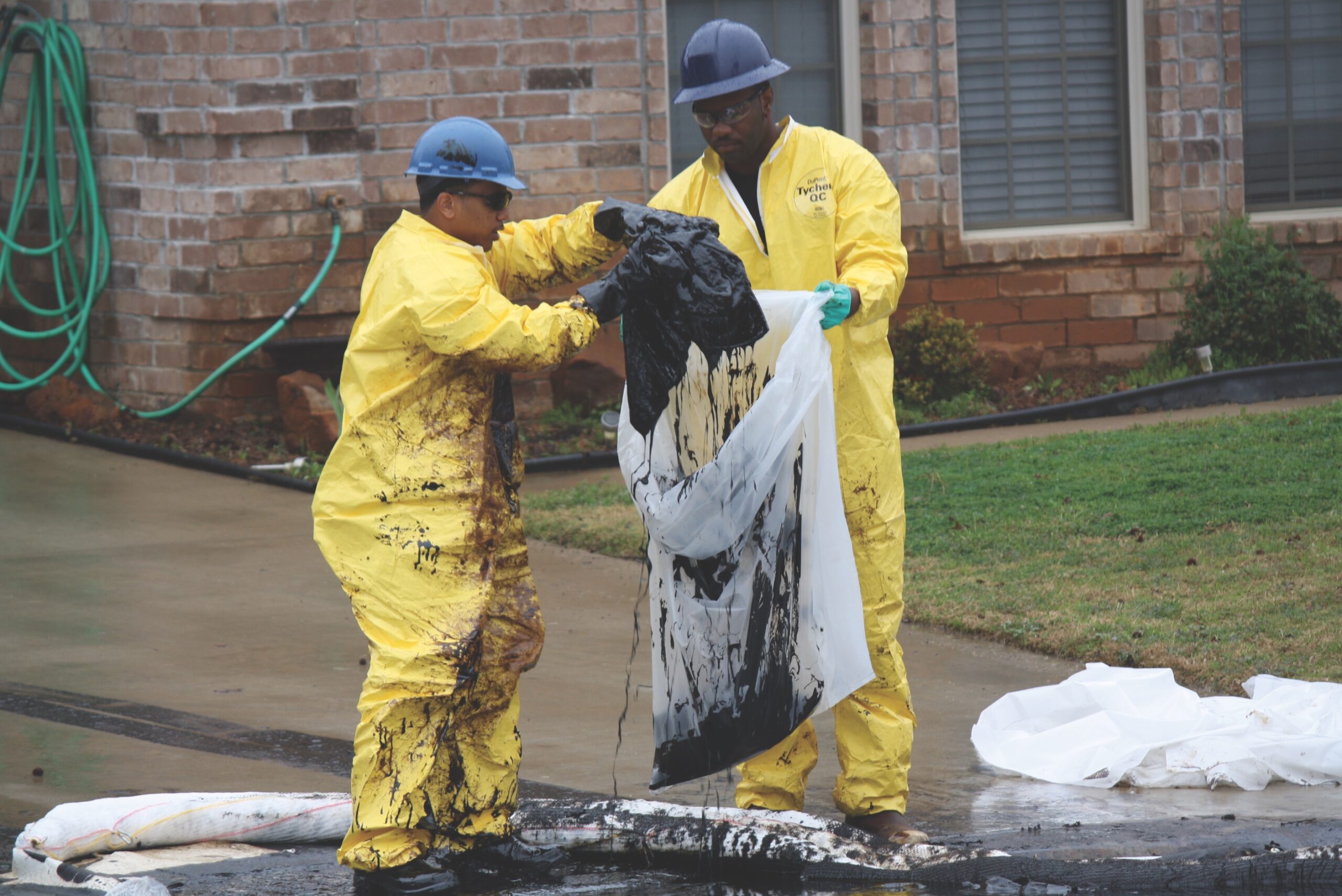 Men in hazmat suits put oil-soaked material in bags