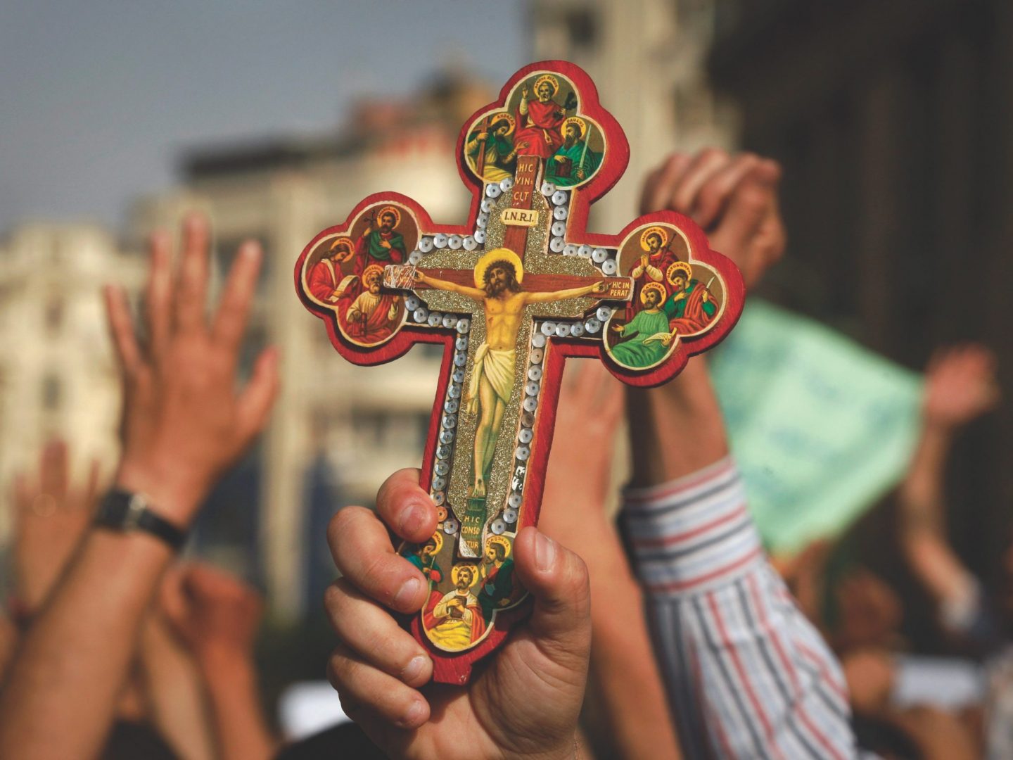 hands holding up Coptic cross