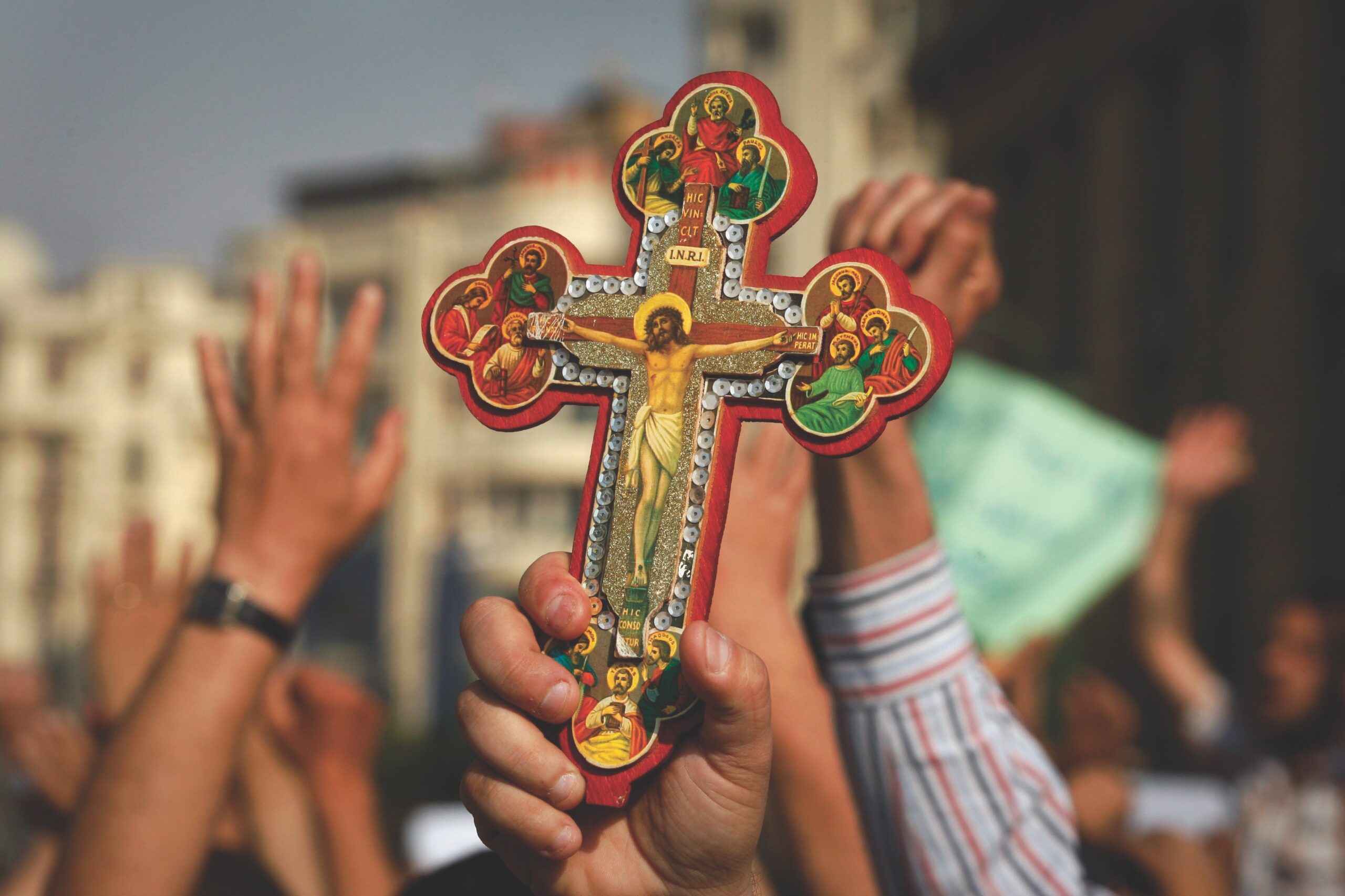 hands holding up Coptic cross
