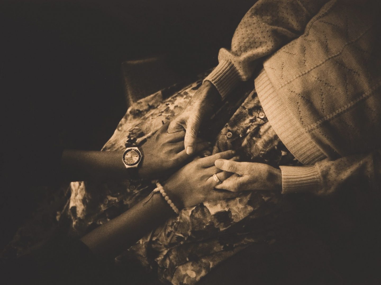 Sepia overhead photo of two women holding hands