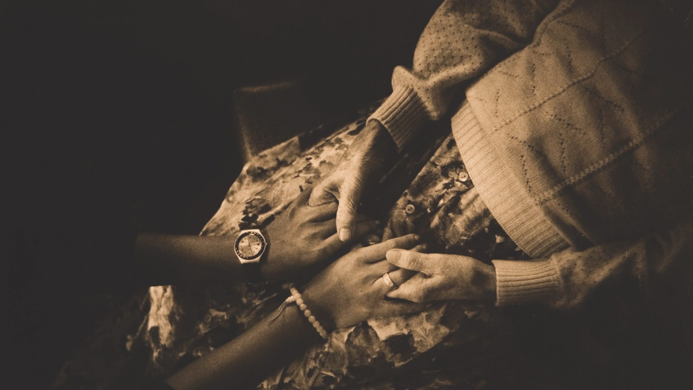 Sepia overhead photo of two women holding hands