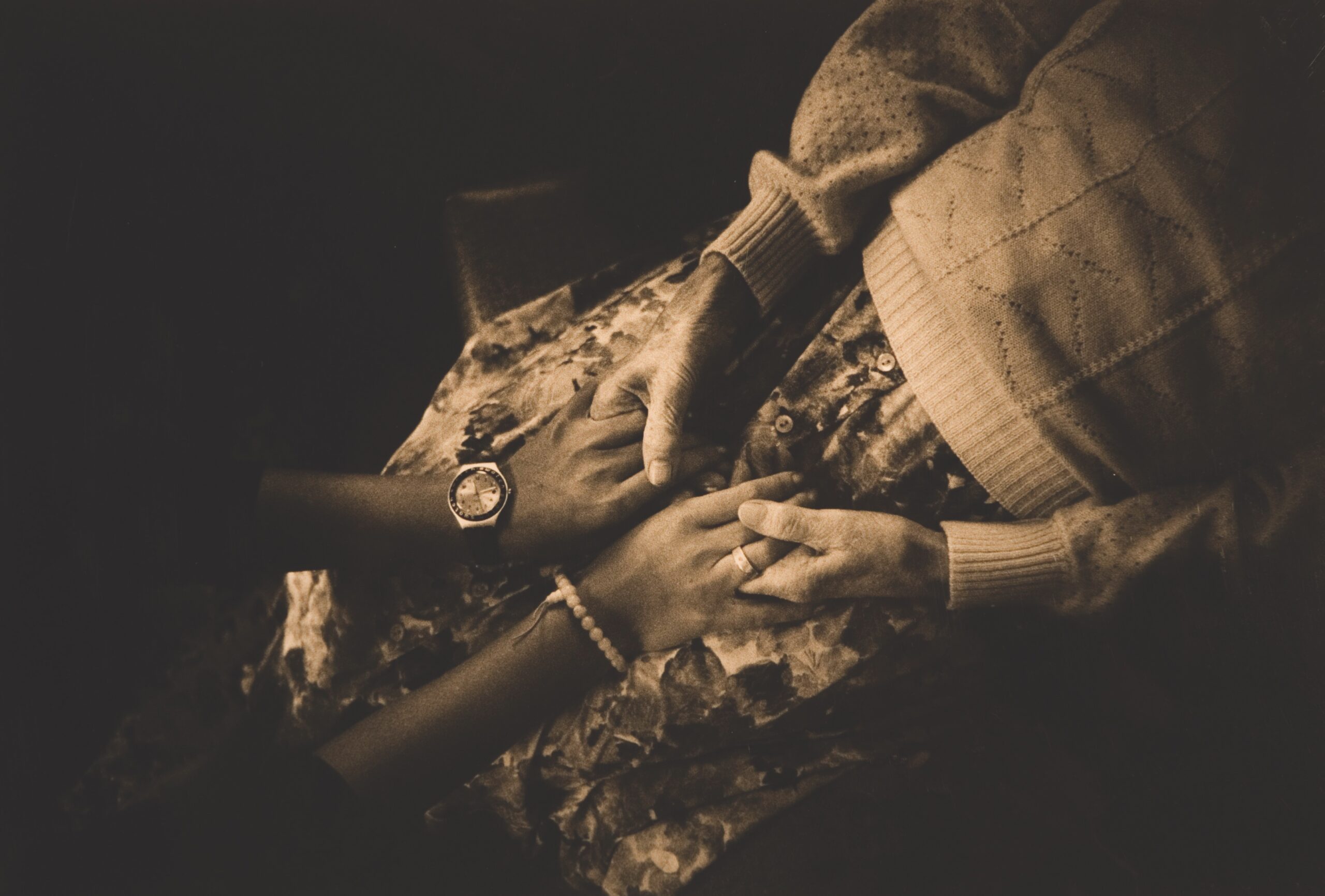 Sepia overhead photo of two women holding hands