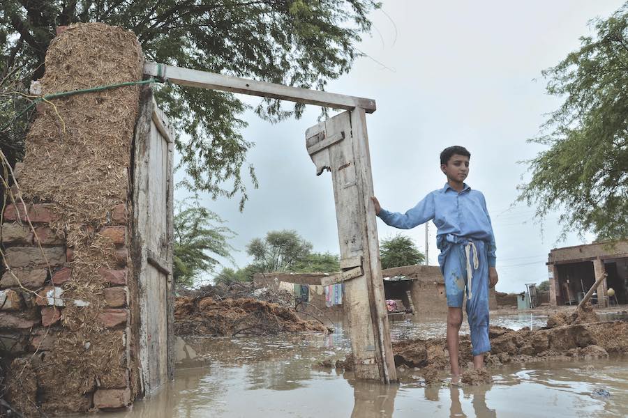 A boy stands in his partially damage home caused by flooding after heavy rains, in Jaffarabad, a district of Pakistan's southwestern Baluchistan province.