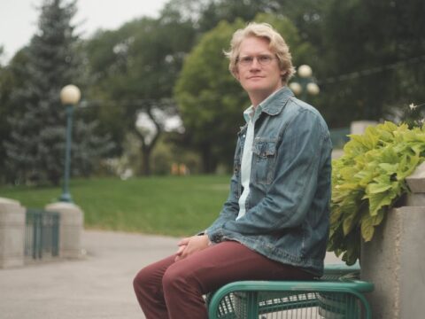 Josiah Neufeld, author of "The Temple at the End of the Universe: A Search for Spirituality in the Anthropocene" sitting on a park bench.