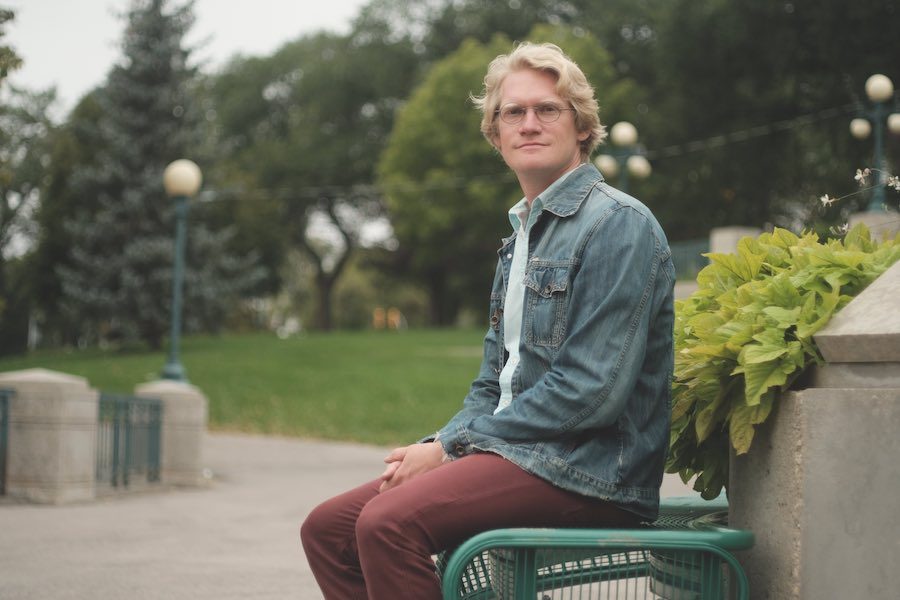 Josiah Neufeld, author of "The Temple at the End of the Universe: A Search for Spirituality in the Anthropocene" sitting on a park bench.