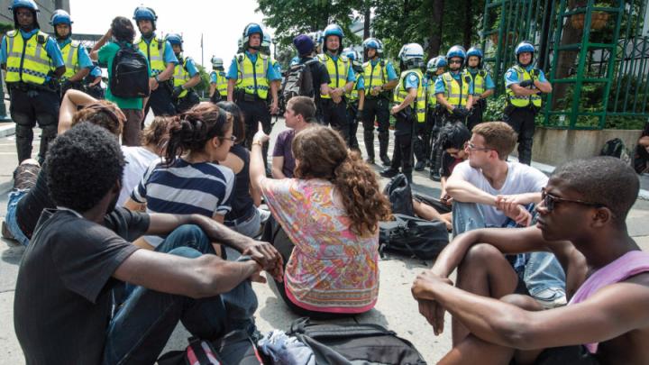 young people sit on street in protest in Montreal