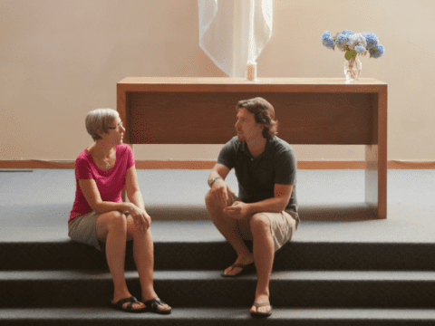 White woman and man sitting on stairs at altar