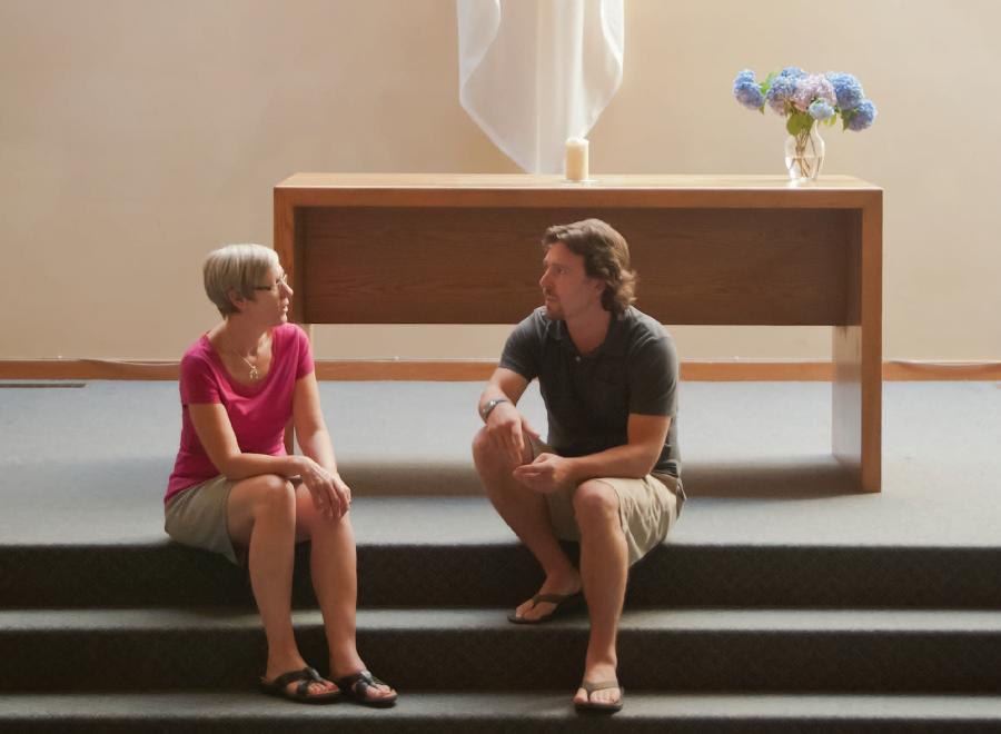 White woman and man sitting on stairs at altar