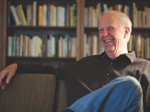 White man sitting in front of bookcase
