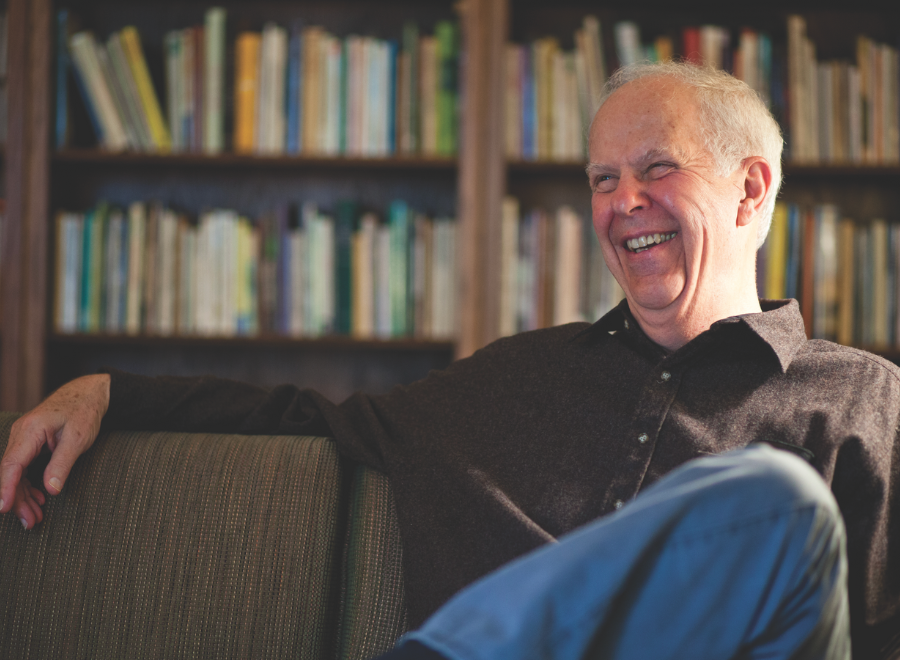 White man sitting in front of bookcase