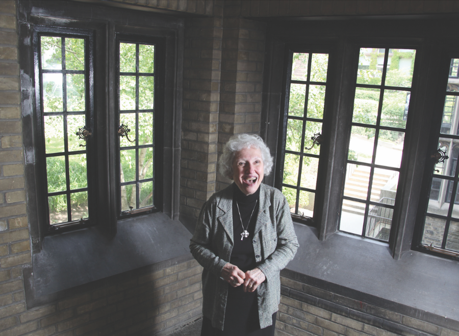 Older white woman standing in front of windows, smiling broadly