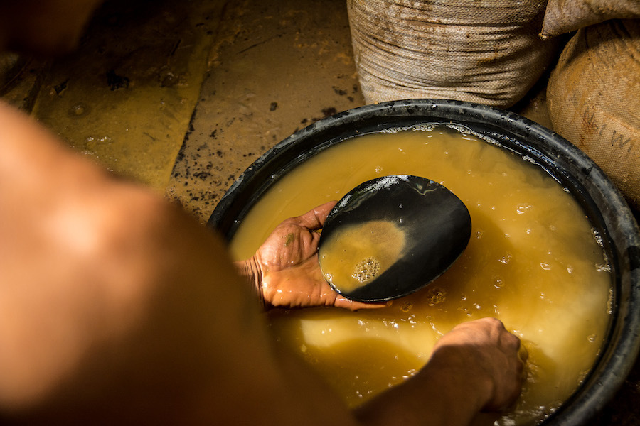 Person holding black clay bowl in dirty brown water held by black clay bowl.