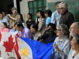 Two rows of people standing and kneeling together. The people kneeling are holding a Canadian flag and a Philippines flag.