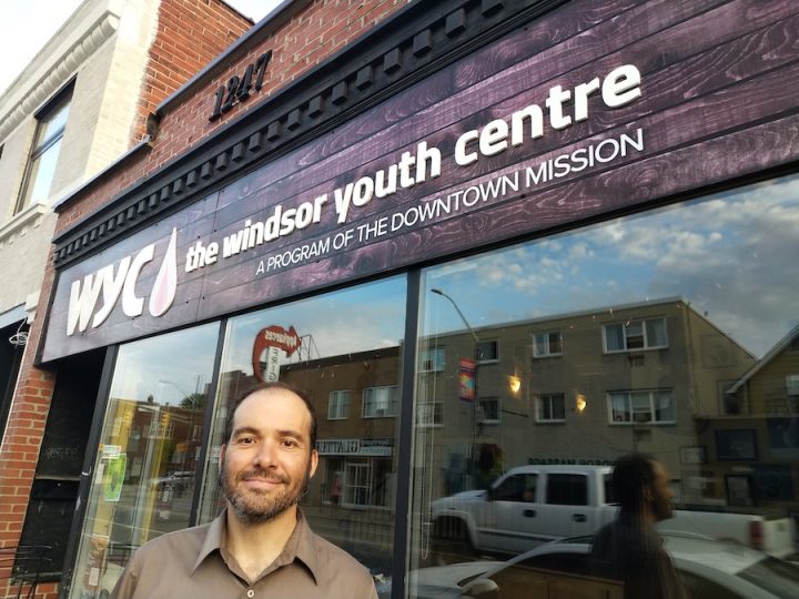 A white man with brown hair and a beard poses in front of the Windsor Youth Centre.