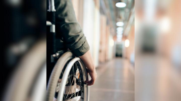 Image of a hand on a wheelchair in a hallway