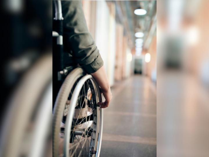 Image of a hand on a wheelchair in a hallway