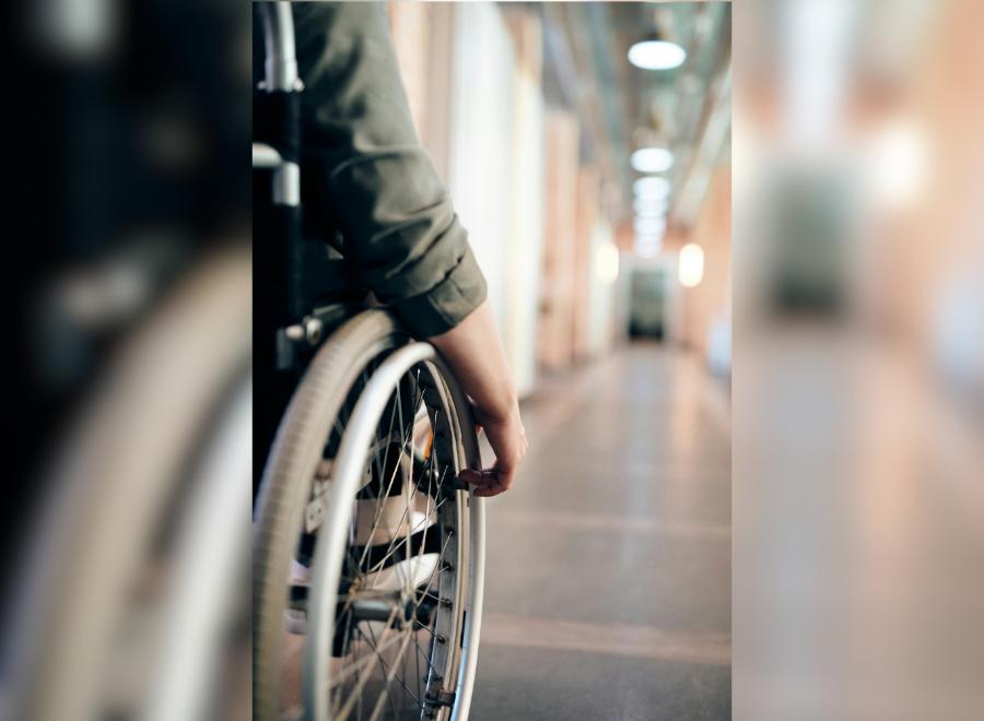 Image of a hand on a wheelchair in a hallway