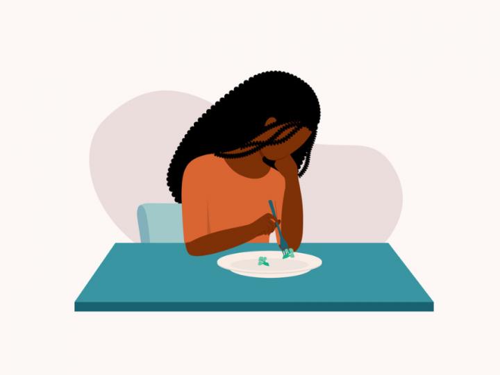 Illustration of a brown-skinned woman sitting at a green table. She is wearing an orange shirt, has dark brown curly hair and she is holding a fork in her right hand. She is piercing a piece of broccoli.